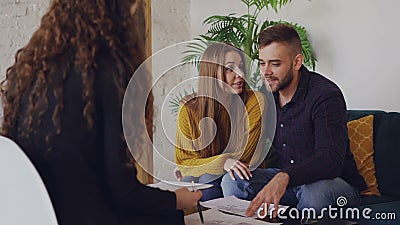 Älska pojkvännen och flickvännen ser plan av huset som de ska köpa och talar till fastighetmäklaren lager videofilmer Älska pojkvännen och flickvännen ser plan av huset som de ska köpa och talar till fastighetmäklaren lager videofilmer
