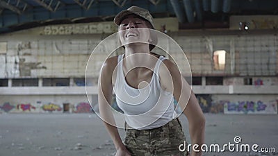 Überzeugte junge Frau im Militäruniformtraining im staubigen schmutzigen verlassenen Gebäude Dünnes Mädchen, das bis zur Kamera l stock video Überzeugte junge Frau im Militäruniformtraining im staubigen schmutzigen verlassenen Gebäude Dünnes Mädchen, das bis zur Kamera l stock video