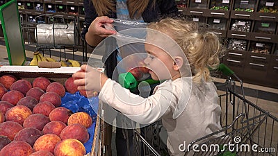 Śliczna mała dziewczynka w zakupy pomocy samochodowej matce podnosić brzoskwini owoc w supermarkecie zbiory wideo Śliczna mała dziewczynka w zakupy pomocy samochodowej matce podnosić brzoskwini owoc w supermarkecie zbiory wideo