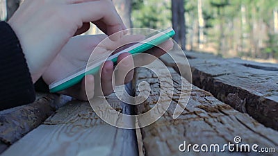 Θηλυκά χέρια που χρησιμοποιούν το smartphone στο όμορφο ξύλινο επιτραπέζιο δάσος υποβάθρου φύσης απόθεμα βίντεο Θηλυκά χέρια που χρησιμοποιούν το smartphone στο όμορφο ξύλινο επιτραπέζιο δάσος υποβάθρου φύσης απόθεμα βίντεο