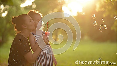 Όμορφη μητέρα με την κόρη της στη φύση που κάνει τις φυσαλίδες και το γέλιο σαπουνιών Όμορφη μητέρα με την κόρη της στη φύση που κάνει τις φυσαλίδες και το γέλιο σαπουνιών