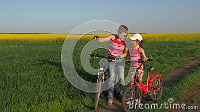 Женщина с ребенком на велосипедах в сельской местности Семья спорт в природе Мама и дочь на велосипедах в поле сток-видео Женщина с ребенком на велосипедах в сельской местности Семья спорт в природе Мама и дочь на велосипедах в поле сток-видео