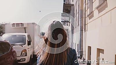 Камера следовать молодой девушкой студента в голубом платье при длинные волосы дуя в ветре идя вдоль замедленного движения улицы сток-видео Камера следовать молодой девушкой студента в голубом платье при длинные волосы дуя в ветре идя вдоль замедленного движения улицы сток-видео
