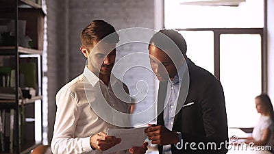 Многорасовые коллеги обсуждают финансовые отчеты в течение рабочего дня Многорасовые коллеги обсуждают финансовые отчеты в течение рабочего дня