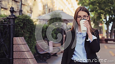 Молодая бизнес-леди идет на улицу и выпивает кофе и smartphone использования на перерыв на ланч акции видеоматериалы Молодая бизнес-леди идет на улицу и выпивает кофе и smartphone использования на перерыв на ланч акции видеоматериалы