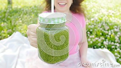 Молодая женщина с зелеными vegetable smoothies в парке видеоматериал Молодая женщина с зелеными vegetable smoothies в парке видеоматериал