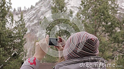 Молодой женский турист фотографирует гора и сосны на ее smartphone видеоматериал Молодой женский турист фотографирует гора и сосны на ее smartphone видеоматериал