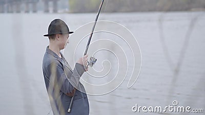 Молодой рыболов в куртке и крышка с наполняются до краев в рыбах scomber задвижки раннего утра с закручивать в реку близко акции видеоматериалы Молодой рыболов в куртке и крышка с наполняются до краев в рыбах scomber задвижки раннего утра с закручивать в реку близко акции видеоматериалы