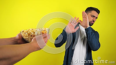 Молодой человек в синей рубашке и белой футболке отказывается от предложенной стеклянной тарелки с попкорном, джунк-кортом видеоматериал Молодой человек в синей рубашке и белой футболке отказывается от предложенной стеклянной тарелки с попкорном, джунк-кортом видеоматериал