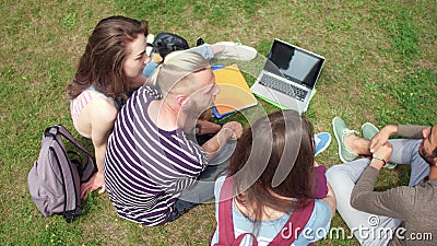  Осмотрите сверху молодых студентов сидя на траве связывая видеоматериал