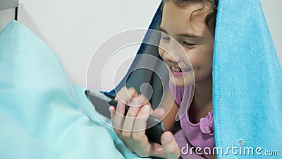 Подросток девушки под одеялом играя в Smartphone маленькая девочка перед крытой кроватью лежит в кровати занимаясь серфингом на и сток-видео - Видео насчитывающей играть, таблетка: 102383923 