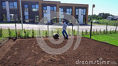 Профессиональный человек работника вытягивает ролик лужайки для сплющивает почву двора Движение карданного подвеса видеоматериал Профессиональный человек работника вытягивает ролик лужайки для сплющивает почву двора Движение карданного подвеса видеоматериал