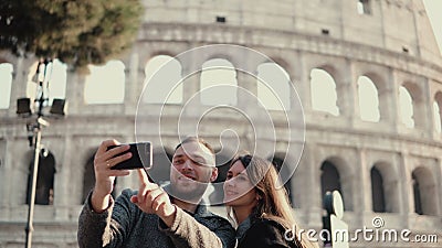 Счастливые молодые пары используя smartphone для принимать фото selfie около Colosseum в Риме, Италии Человек и женщина имеют кан видеоматериал Счастливые молодые пары используя smartphone для принимать фото selfie около Colosseum в Риме, Италии Человек и женщина имеют кан видеоматериал