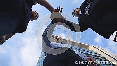 Успешные бизнесмены стоя и штабелированные руки совместно около офисного здания Мужские коллеги кладя их оружия внутри сток-видео Успешные бизнесмены стоя и штабелированные руки совместно около офисного здания Мужские коллеги кладя их оружия внутри сток-видео