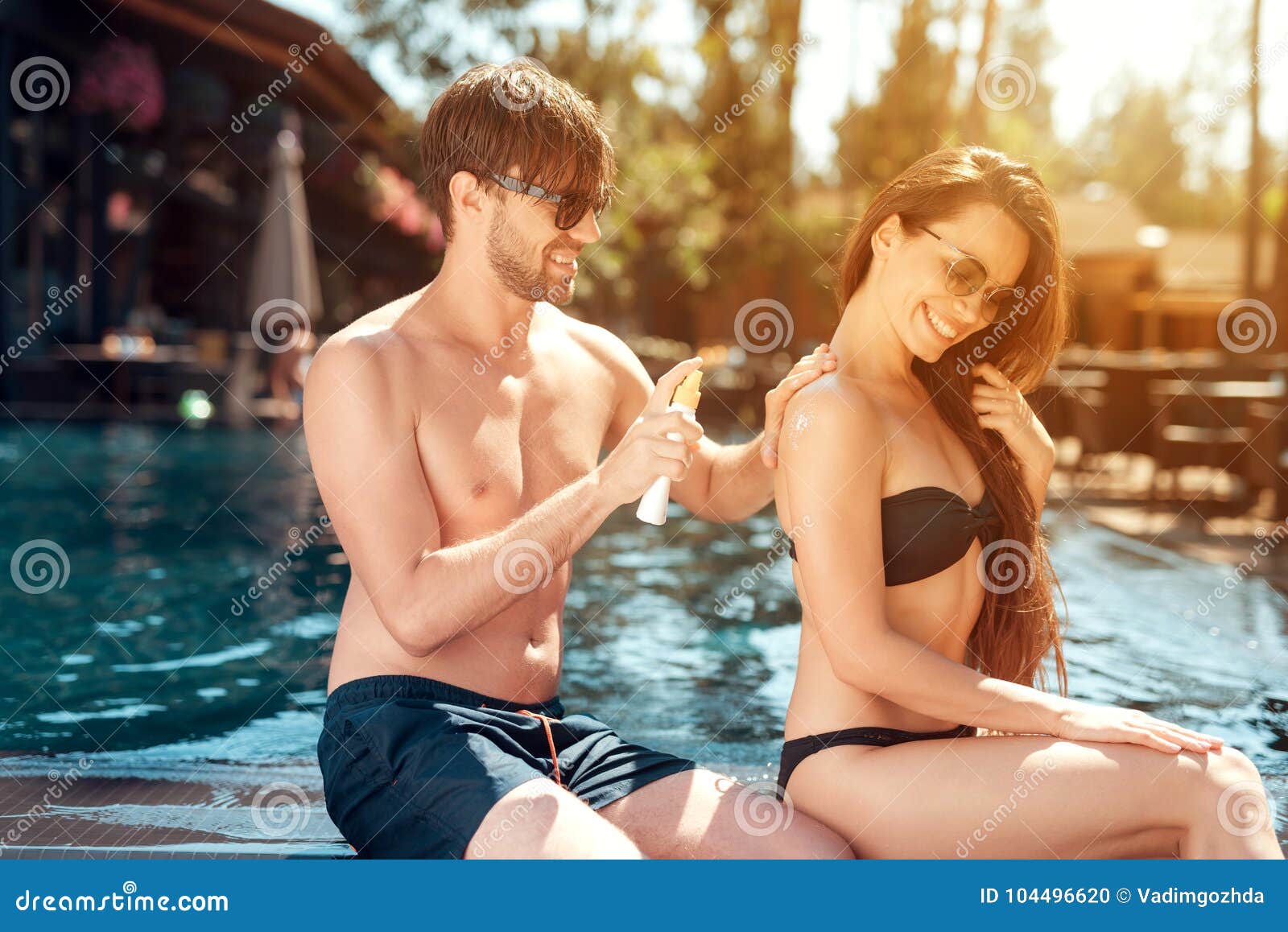 Парни трут девушек. Парень мажет девушку кремом на пляже. Девушка мажет парня кремом. Женщина и мужчина фотосессия возле бассейна. Парень с девушкой около бассейна.
