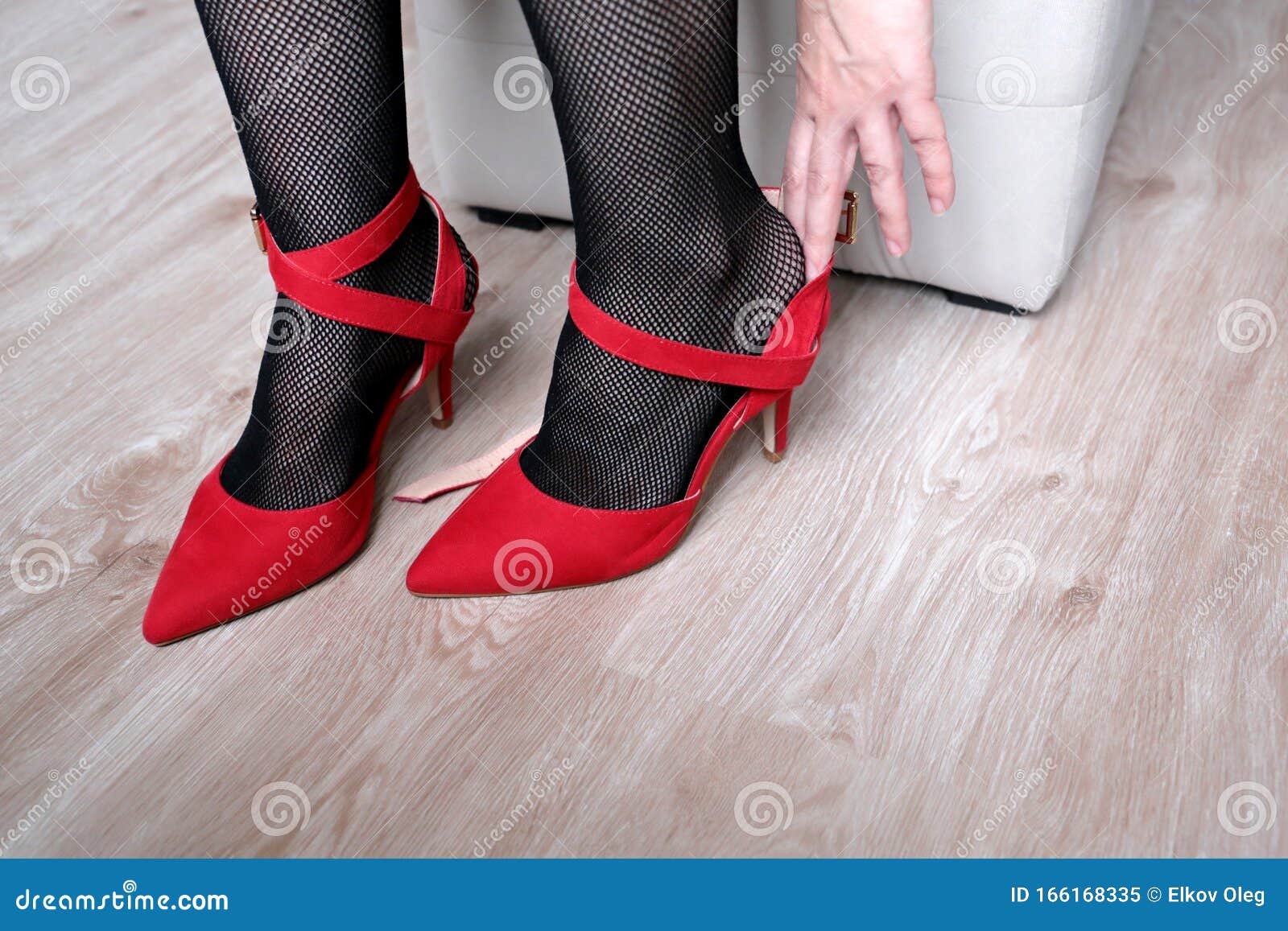 Γυναίκα με μαύρες κάλτσες που δοκιμάζει κόκκινα παπούτσια με ψηλά τακούνια  Στοκ Εικόνα - εικόνα από bodybuilders, bedroll: 166168335