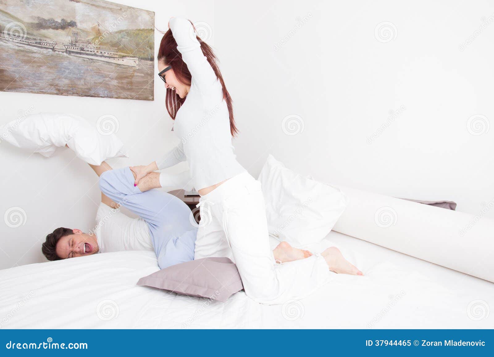 Γυναίκα στις πυτζάμες που χτυπούν τον άνδρα με το μαξιλάρι ενώ αυτός Στοκ  Εικόνα - εικόνα από lifestyles, bedroll: 37944465