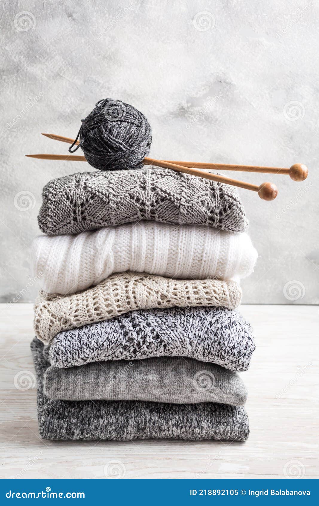 στοίβα από ζεστά πλεκτά πουλόβερ και πουλόβερ με βελόνες πλέξης σε ξύλινο  φόντο Στοκ Εικόνα - εικόνα από lifestyle: 218892105