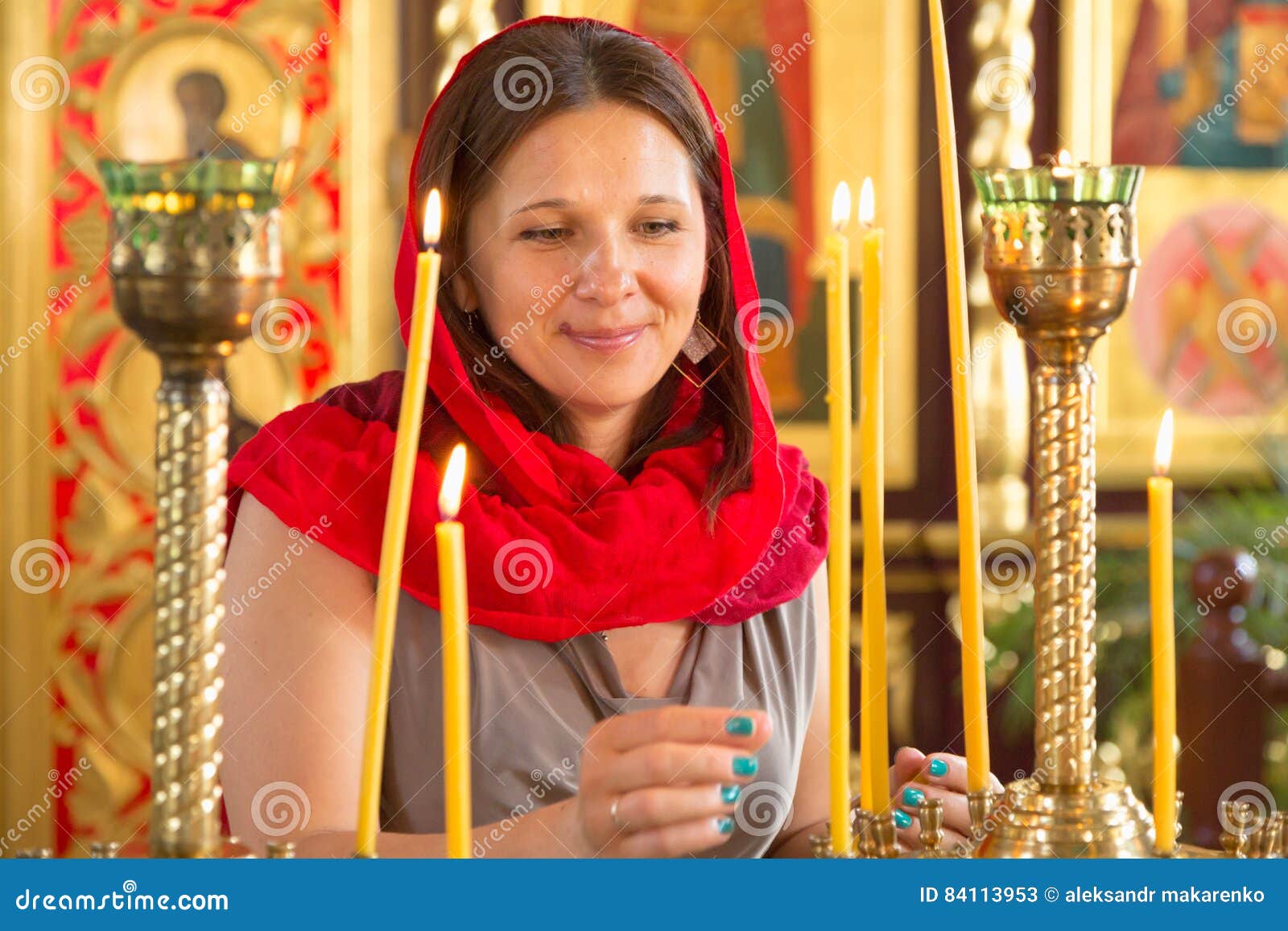 Το όμορφο κορίτσι σε ένα κόκκινο μαντίλι βάζει τα κεριά σε μια ορθόδοξη  χριστιανική εκκλησία Στοκ Εικόνα - εικόνα από : 84113953