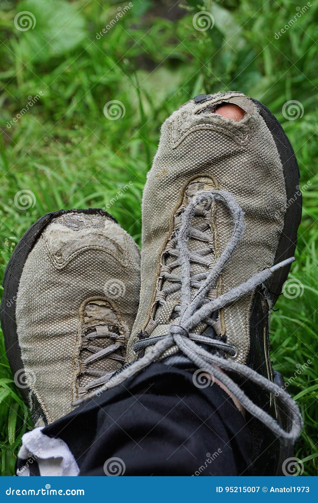 Τρύπα σε ένα γκρίζο πάνινο παπούτσι σε ένα πόδι στη χλόη Στοκ Εικόνα -  εικόνα από holey, accidence: 95215007