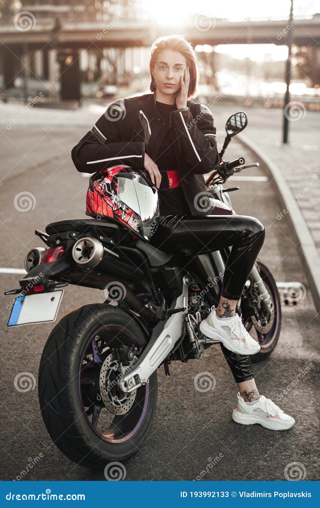 όμορφο κορίτσι με σακάκι κάθεται σε μια μωβ μοτοσικλέτα με κόκκινο και  μαύρο κράνο ασφαλείας Στοκ Εικόνα - εικόνα από : 193992133