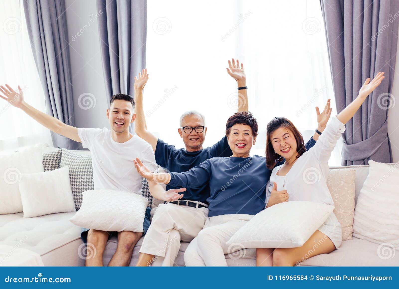 Азиатская семья при взрослые дети и старшие родители поднимая руки вверх и  сидя на софе дома Счастливое и расслабляющее время сем Стоковое Фото -  изображение насчитывающей кресло, камера: 116965584