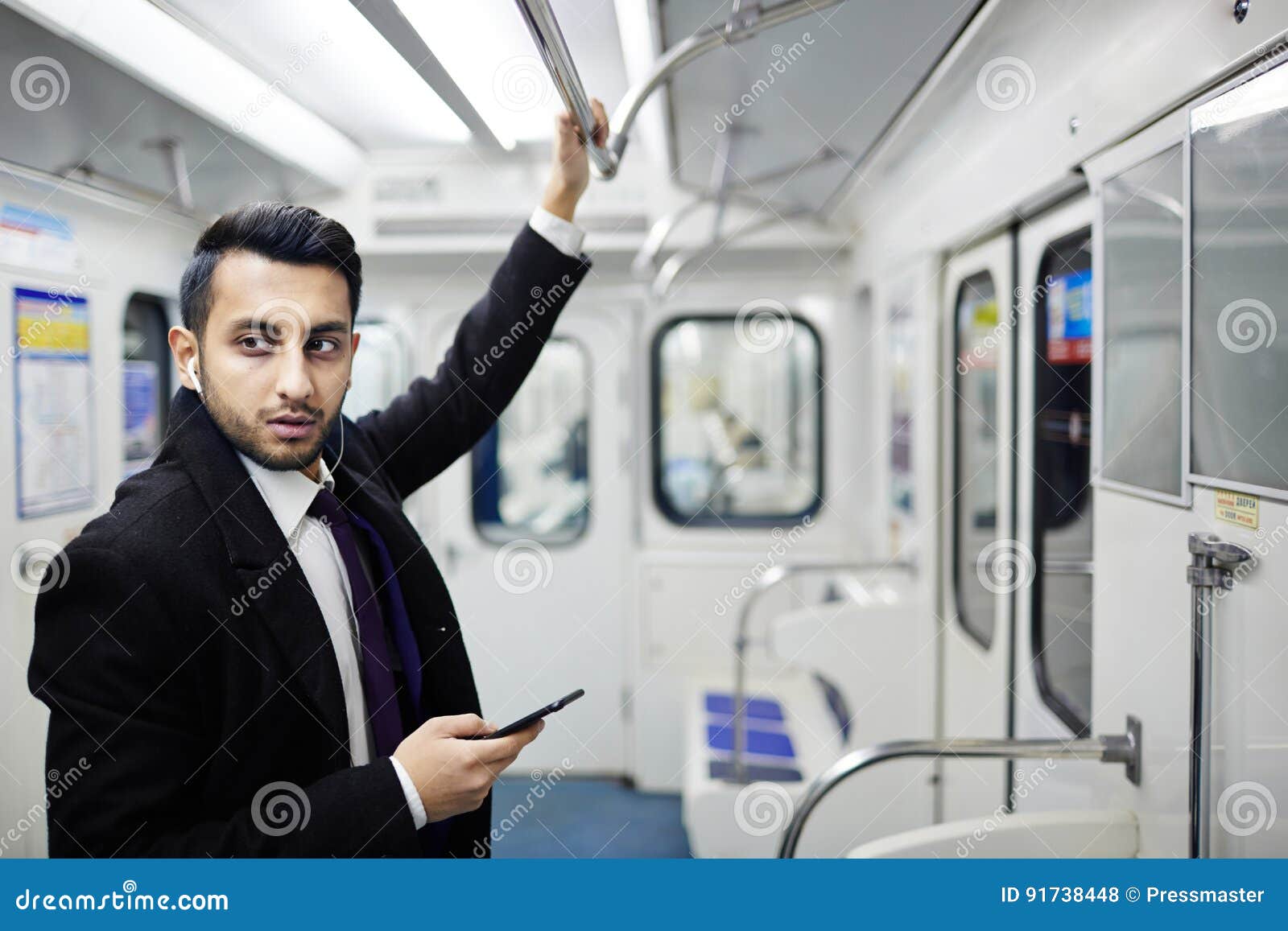 Человек держится за поручень в автобусе. Держится за поручень в метро. Человек в метро фотосток. Люди в метро стоя.