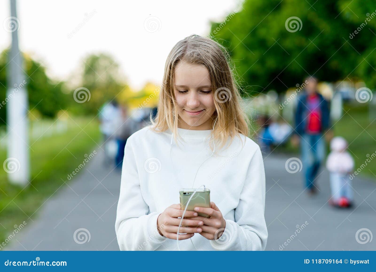 Блондинка школьницы девушки Лето в природе В руках держа Smartphone слушая  к музыке на телефоне Связывает внутри Стоковое Фото - изображение  насчитывающей кампус, привлекательностей: 118709164