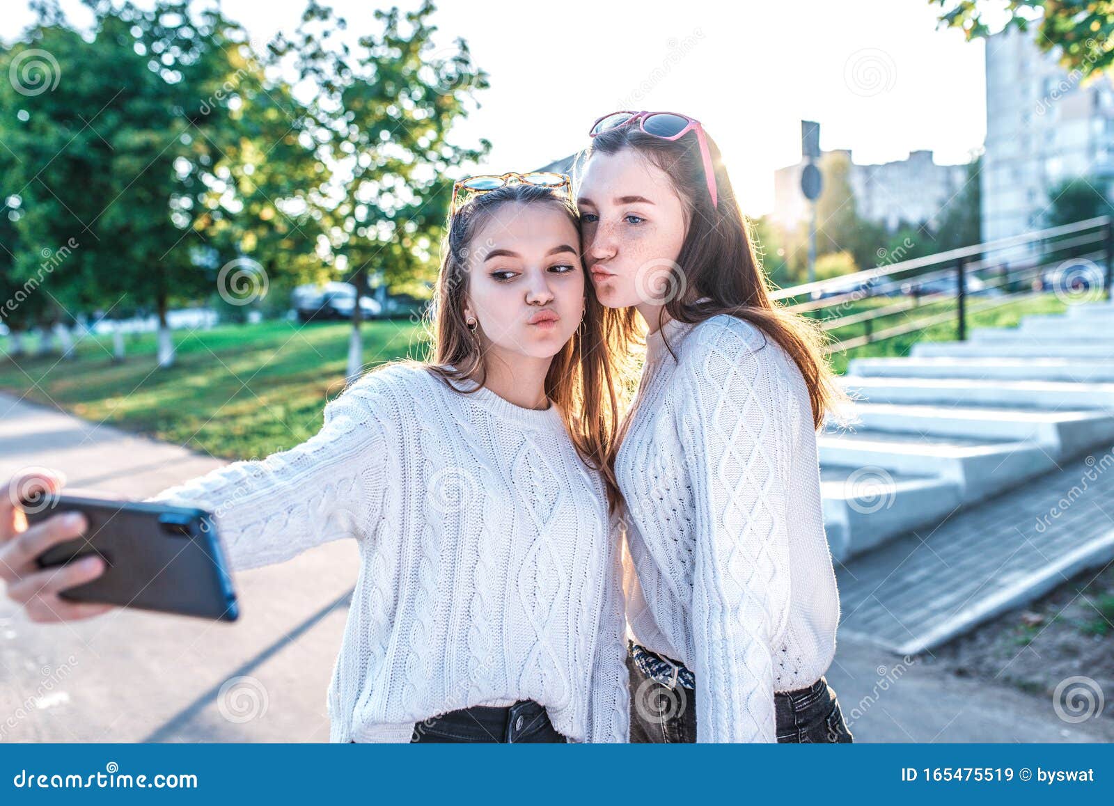 Две школьницы-подростки в возрасте 12-15 лет, в осеннем летнем городе, в  руках смартфона, селфи фото, видео Стоковое Изображение - изображение  насчитывающей персона, клетка: 165475519