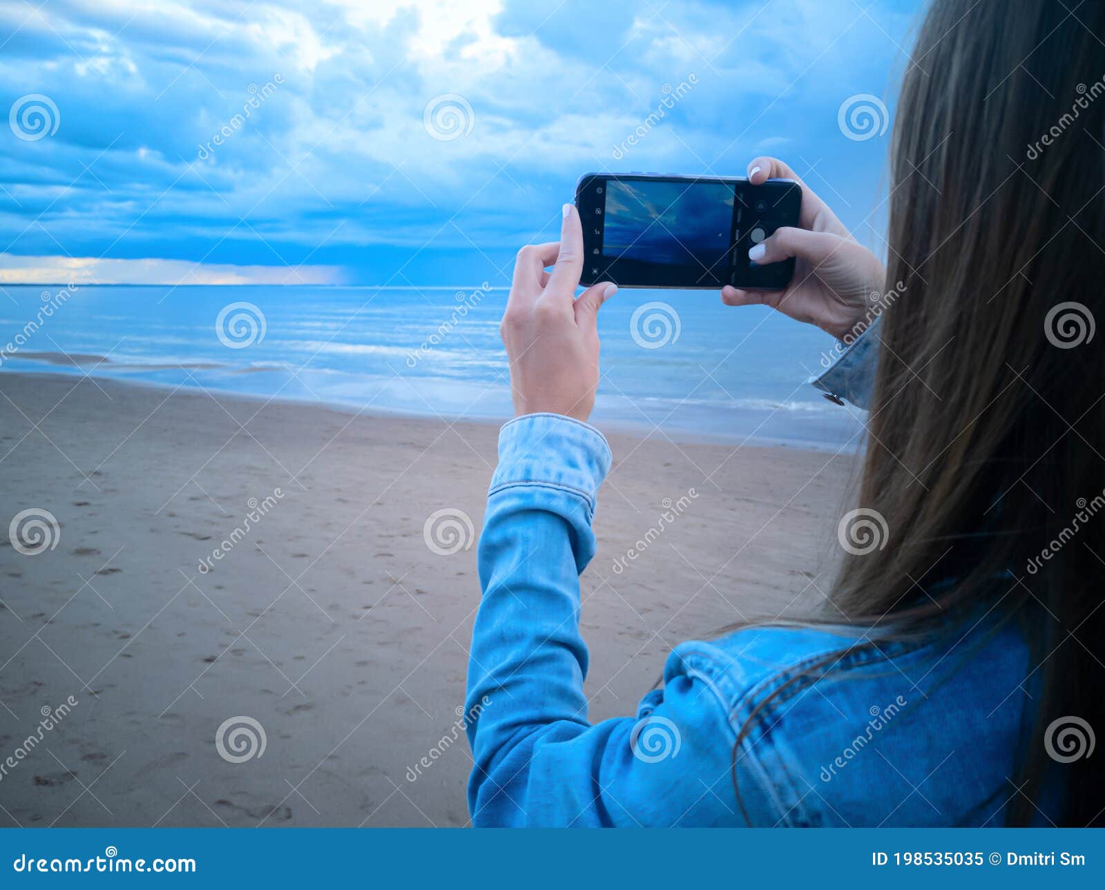 Девушка фотографируется на море.