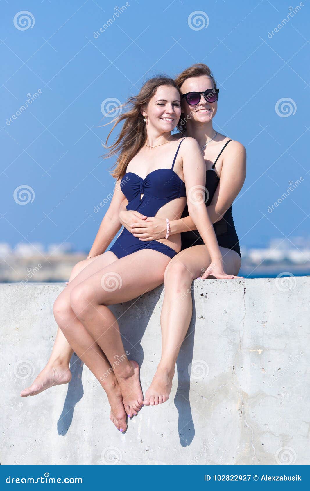 2 девушки в цельных купальниках сидят одна после другой Стоковое  Изображение - изображение насчитывающей после, представлять: 102822927