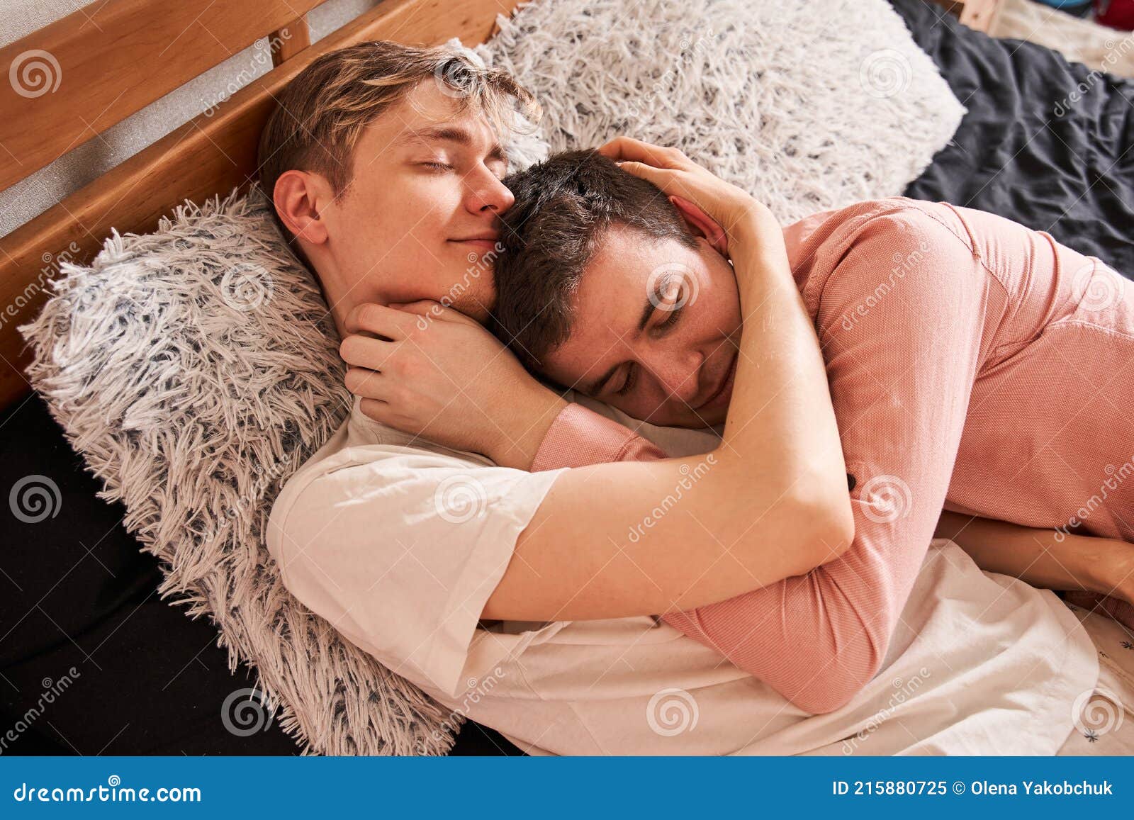 довольный гей обнимает своего парня, пока лежит с ним у кровати Стоковое Изображение - изображение насчитывающей отдых, гомосексуально: 215880725