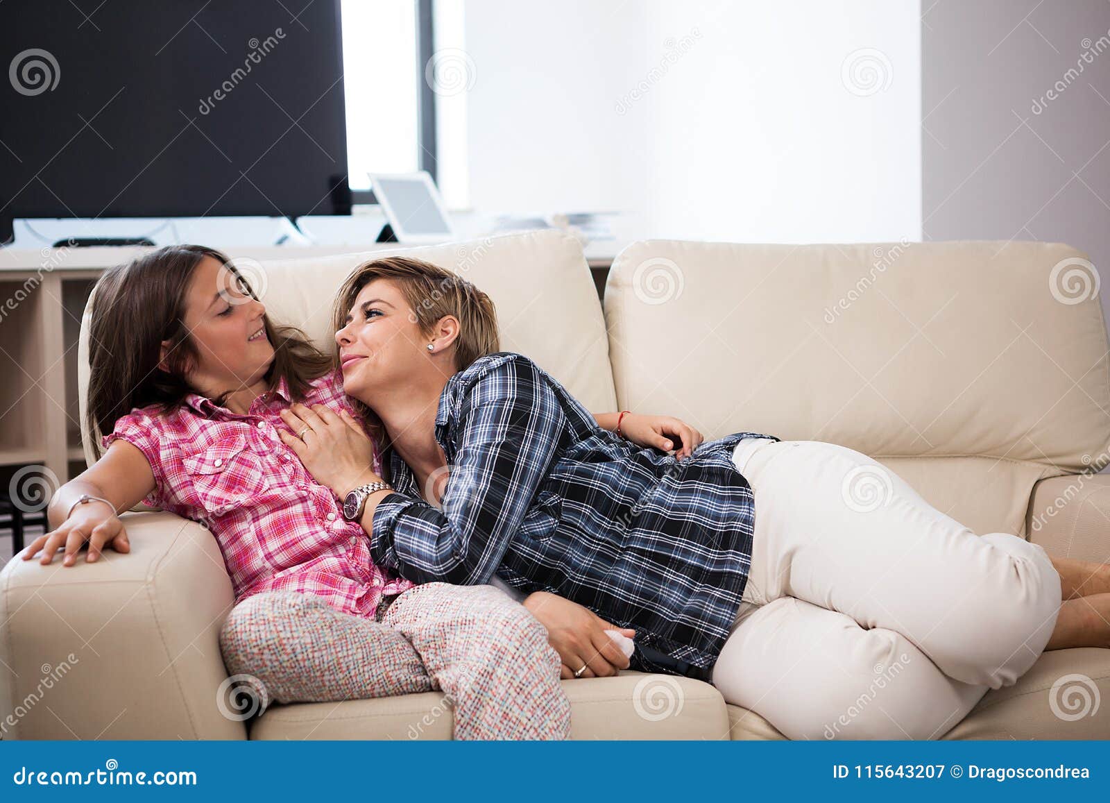 Русская мама с дочкой занимаются. Дочь лежит на матери. Дочь лежит у мамы на коленях. Дочка лежит на маме. Мама на диване.