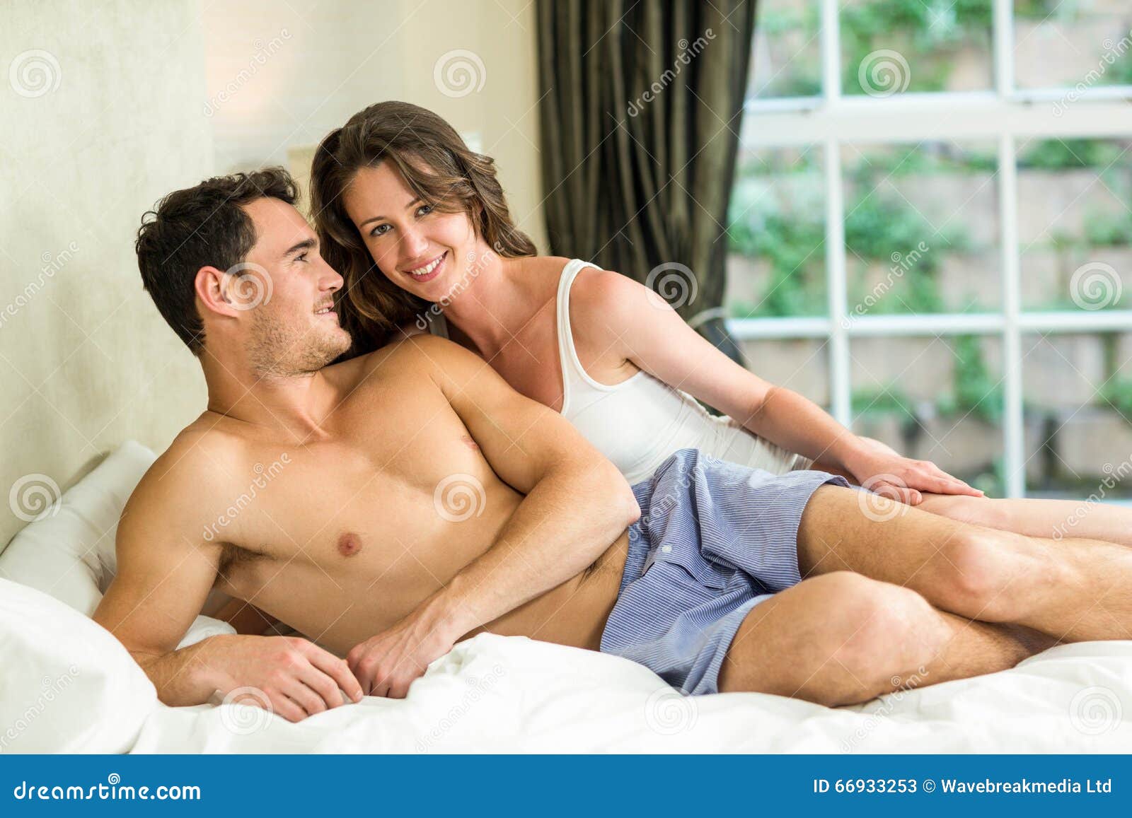 Молодые расслабляются. Расслабленная молодая пара в постели. Молодая пара отдыхает в постели. Молодая пара в кровати. Сорокалетние парочки в постели.