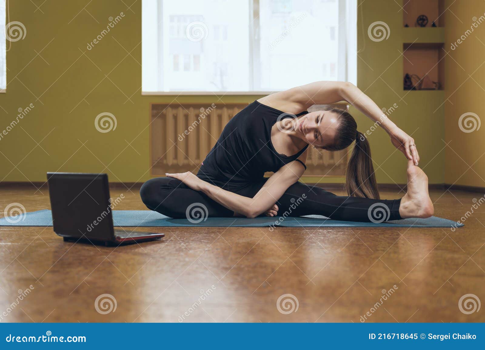 женщина в черной спортивной одежде делает йога выполняет онлайн упражнения Parivritta джану Shirshasana смотрит в ноутбук Стоковое Изображение - изображение насчитывающей смотрит, концентрация: 216718645