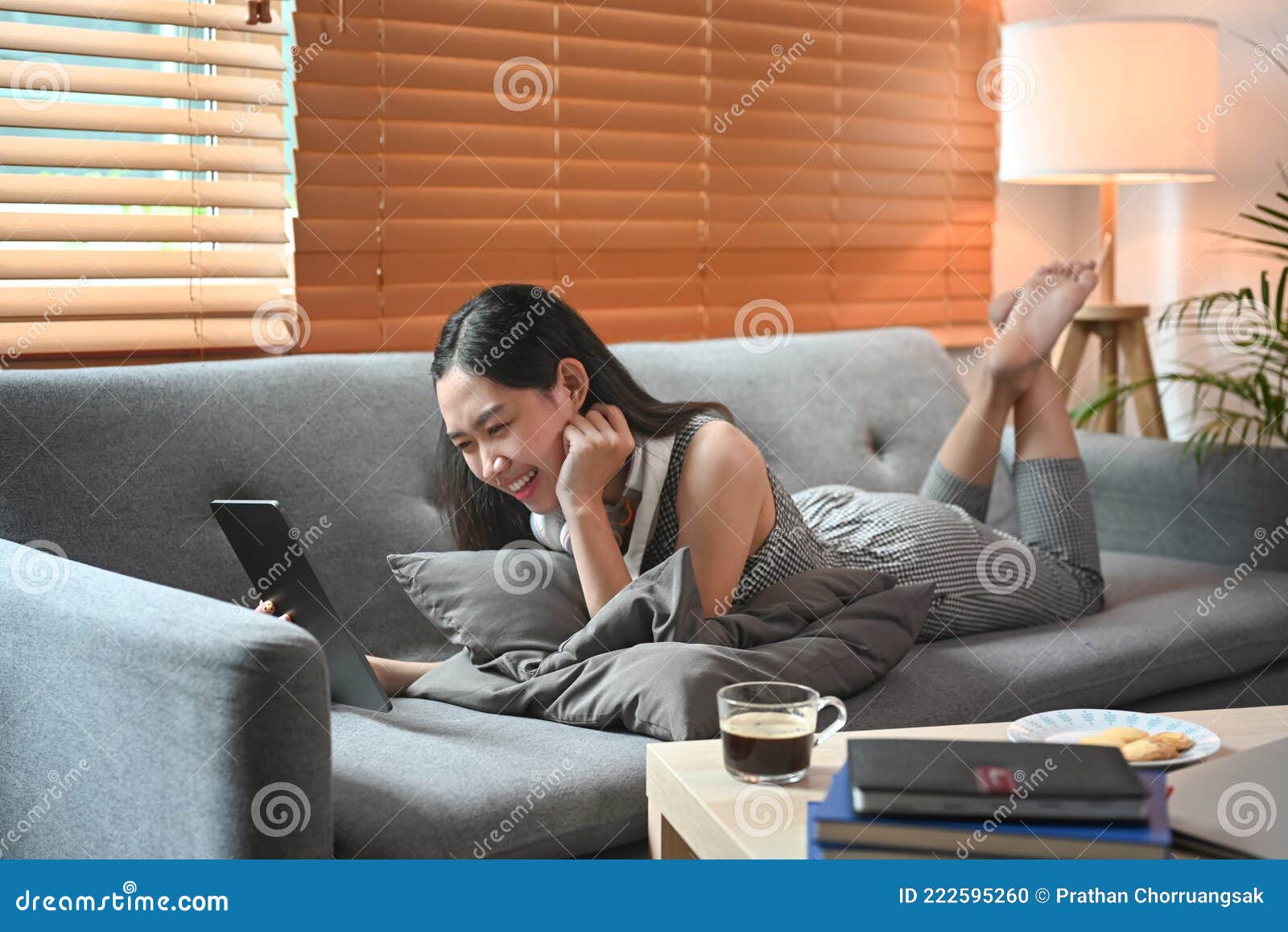 женщина лежит на диване в гостиной и просматривает интернет с планшетом.Стоковое Фото - изображение насчитывающей интернет, отдых: 222595260