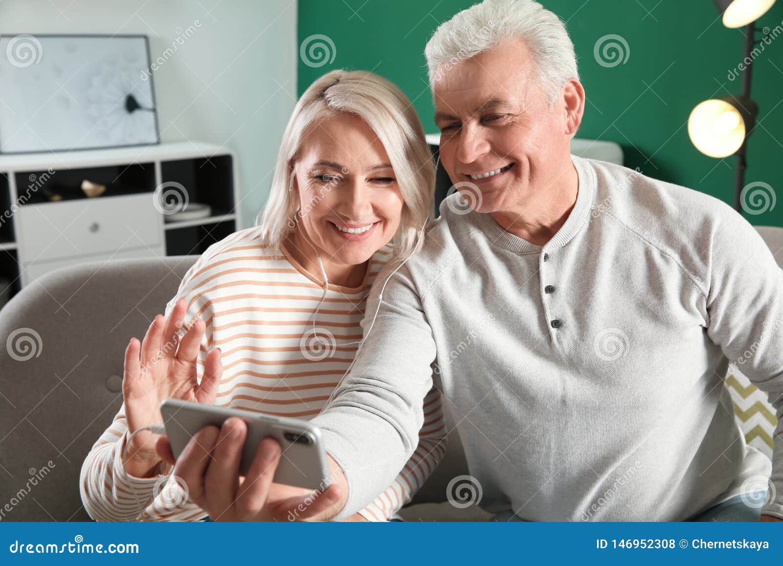 Зрелые пары используя видео-чат на мобильном телефоне Стоковое Фото -  изображение насчитывающей возмужало, цифрово: 146952308