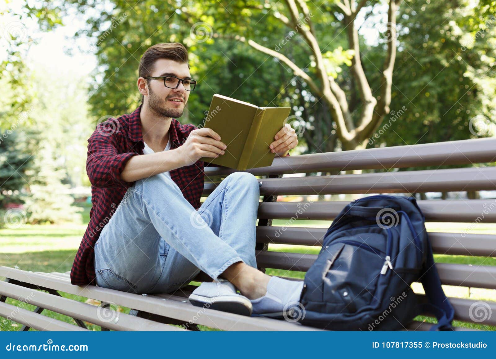 Preparing for reading. Человек читает. Мужчина с книжкой в парке. Парень с книгой в парке. Мужчина улыбается в парке.