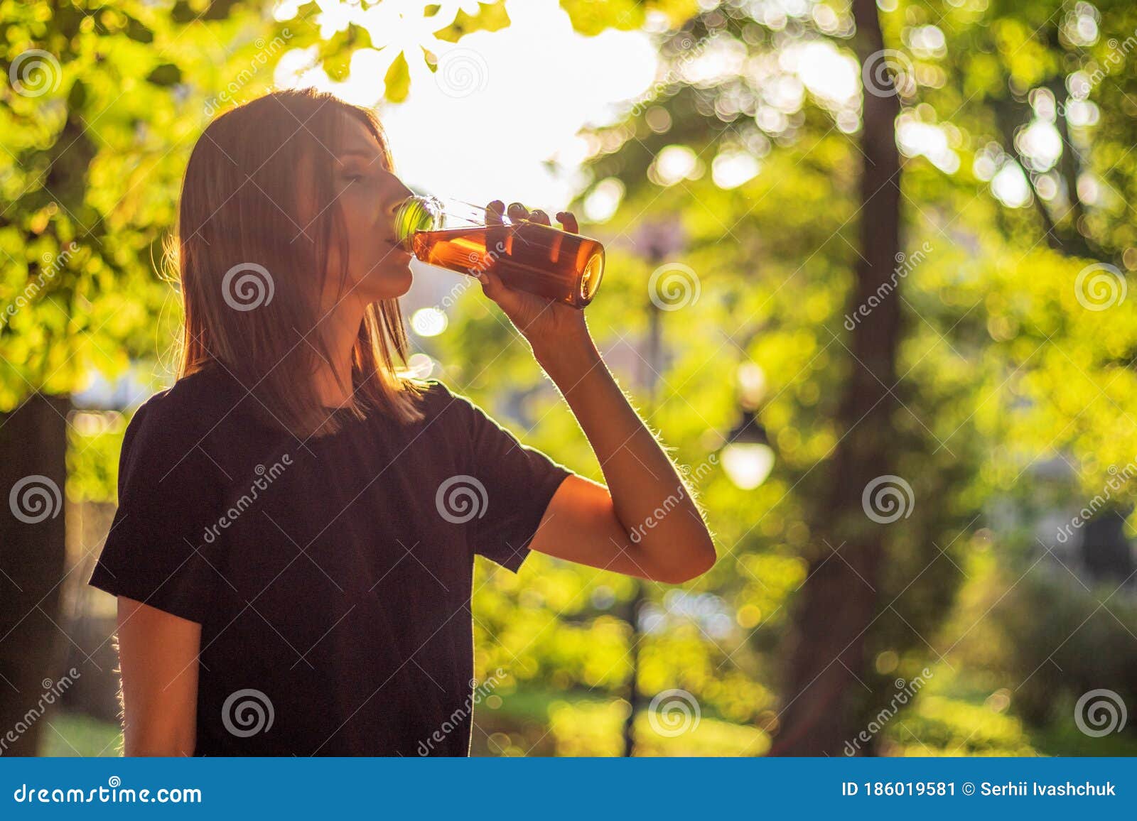 Красивая женщина пьет чай со льдом фитнес-залом спортсмена после тренировки, работающих в вечернее время заката в парке. Стоковое Изображение - изображение насчитывающей сок, черный: 186019581