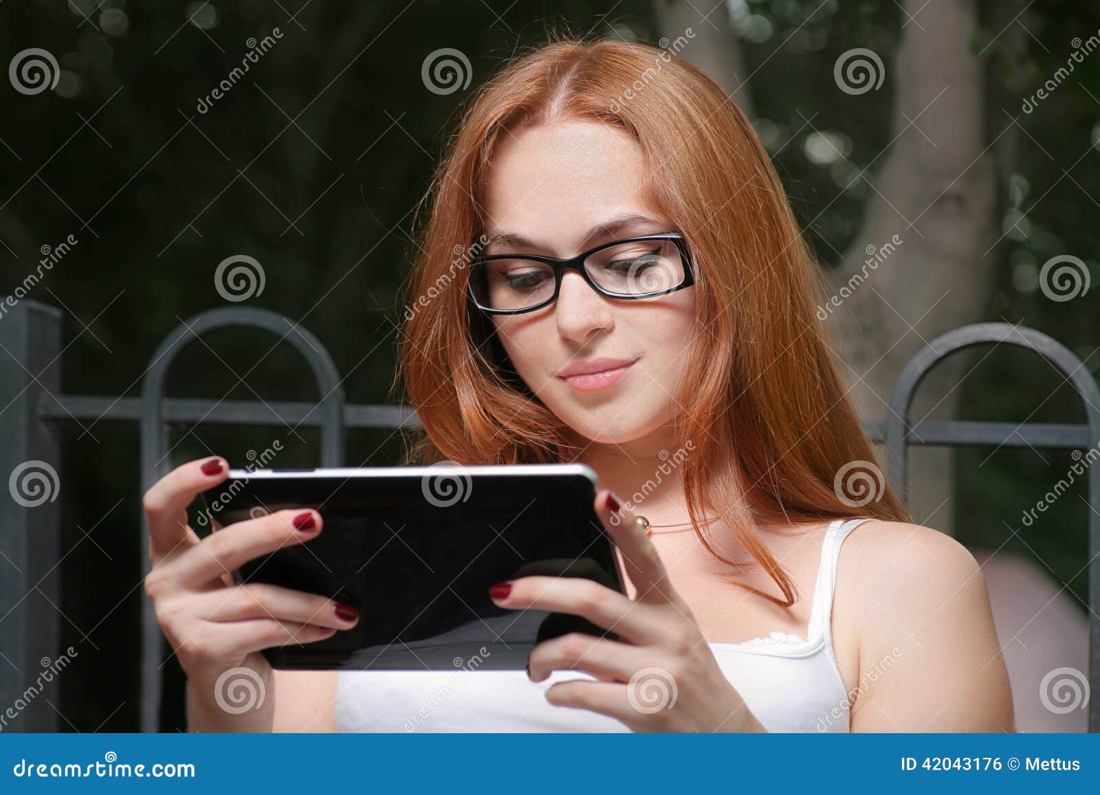 Красивая молодая женщина Redhead с таблетк-ПК в склонности парка используя  сенсорный экран Стоковое Фото - изображение насчитывающей интернет,  счастливо: 42043176