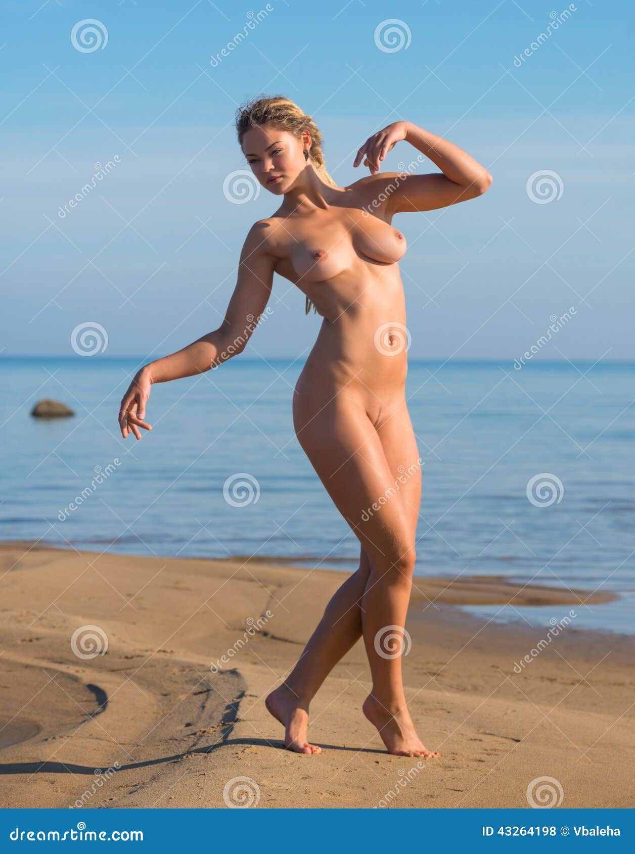 Красивая нагая женщина представляя на пляже 