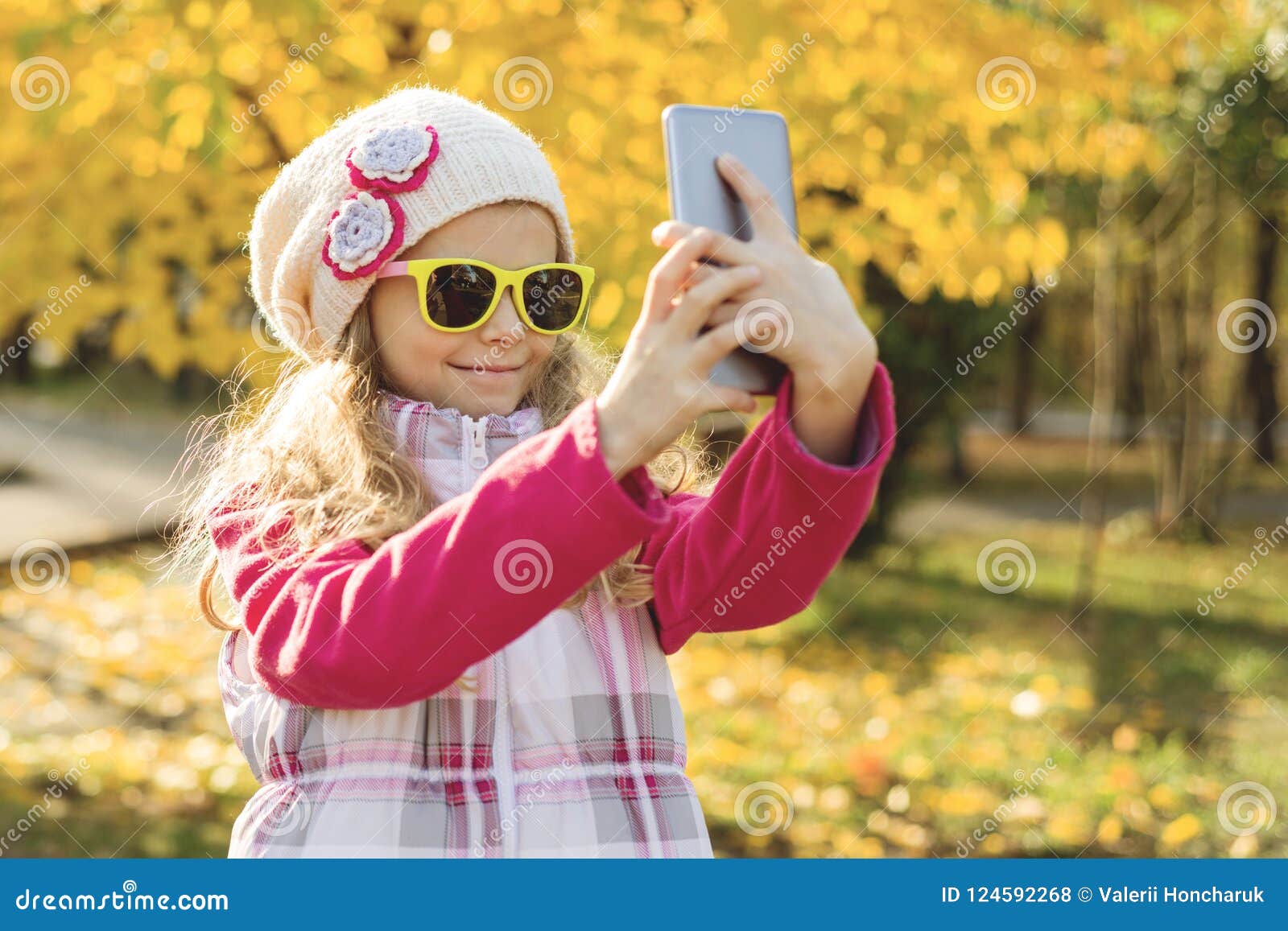 Милая девушка 7 лет делая Selfie используя Smartphone, предпосылку осени  Стоковое Фото - изображение насчитывающей ребенок, наслаждаться: 124592268