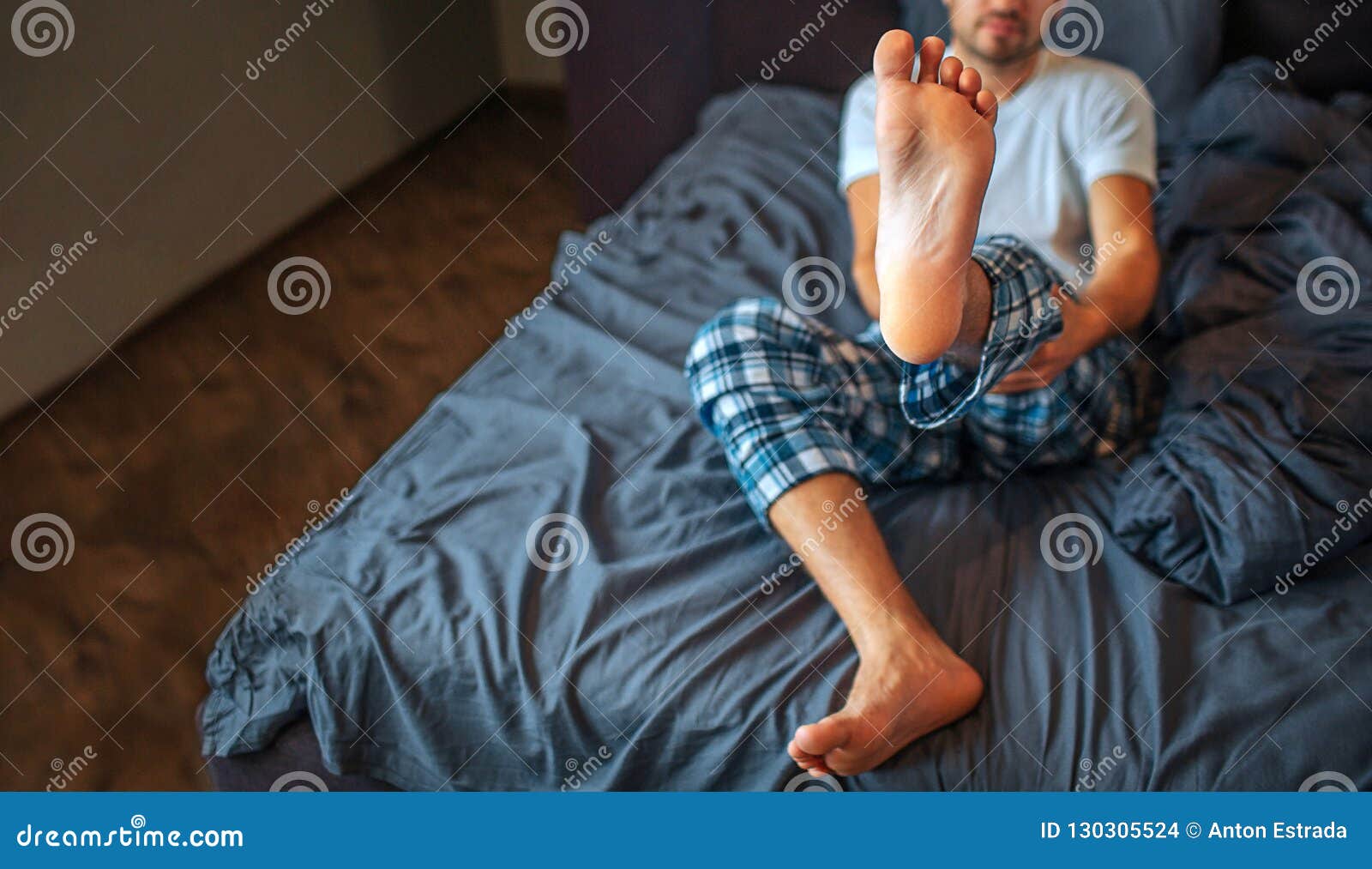 Мужчина показывает ногу. Мужские ноги на кровати. Мужские ноги в постели. Человек сидит на кровати. Нога за ногу мужчина.