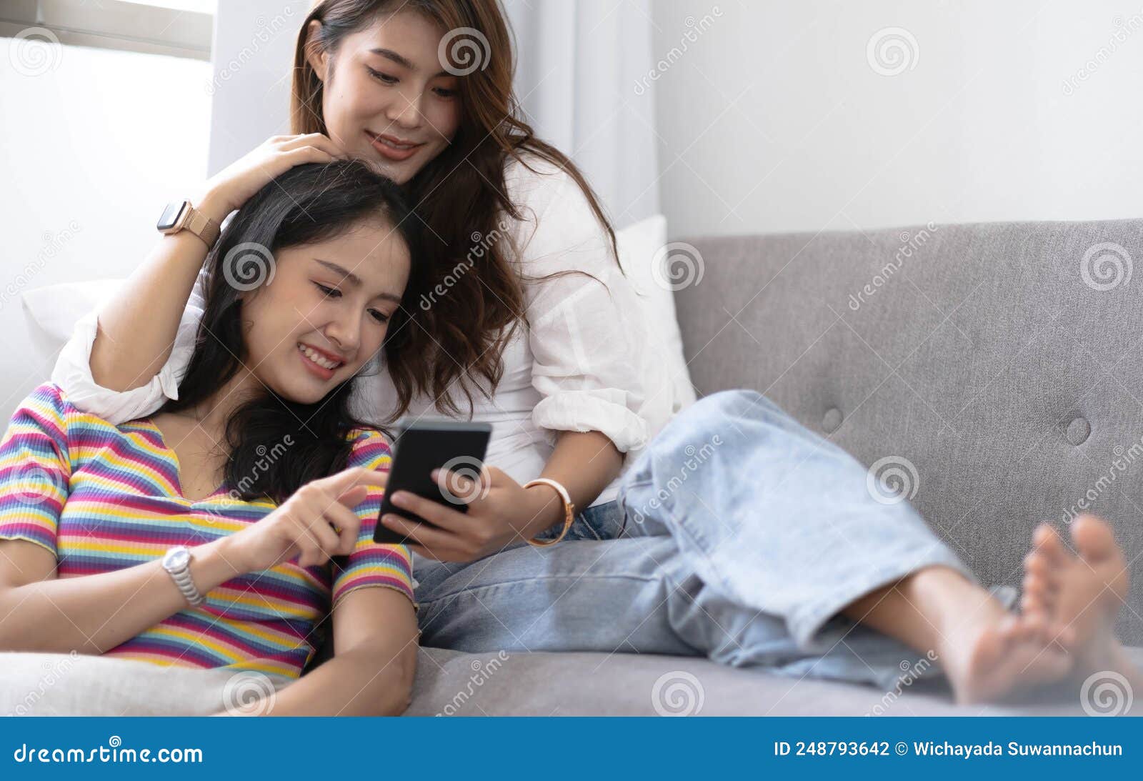 молодые красивые азиатки-лесбиянки любовницы, которые пользуются  смартфонным видеозвонком в гостиной на диване дома с улыбкой Стоковое Фото  - изображение насчитывающей счастливо, красиво: 248793642