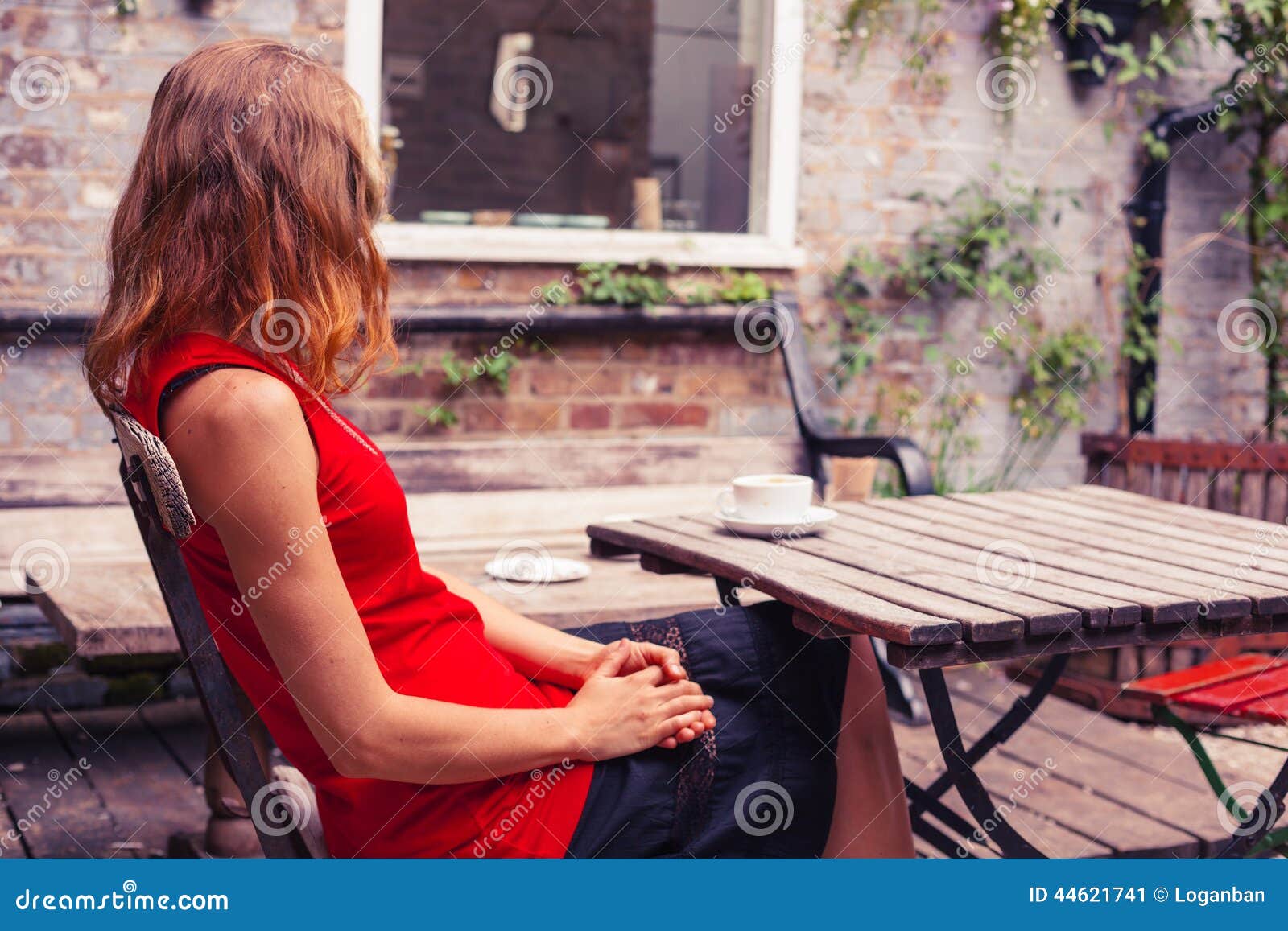 фрилансер. The woman is sitting a table. девушка ставит чашку на стол. девушка сидит за столом спиной. за столом пара интерьер.