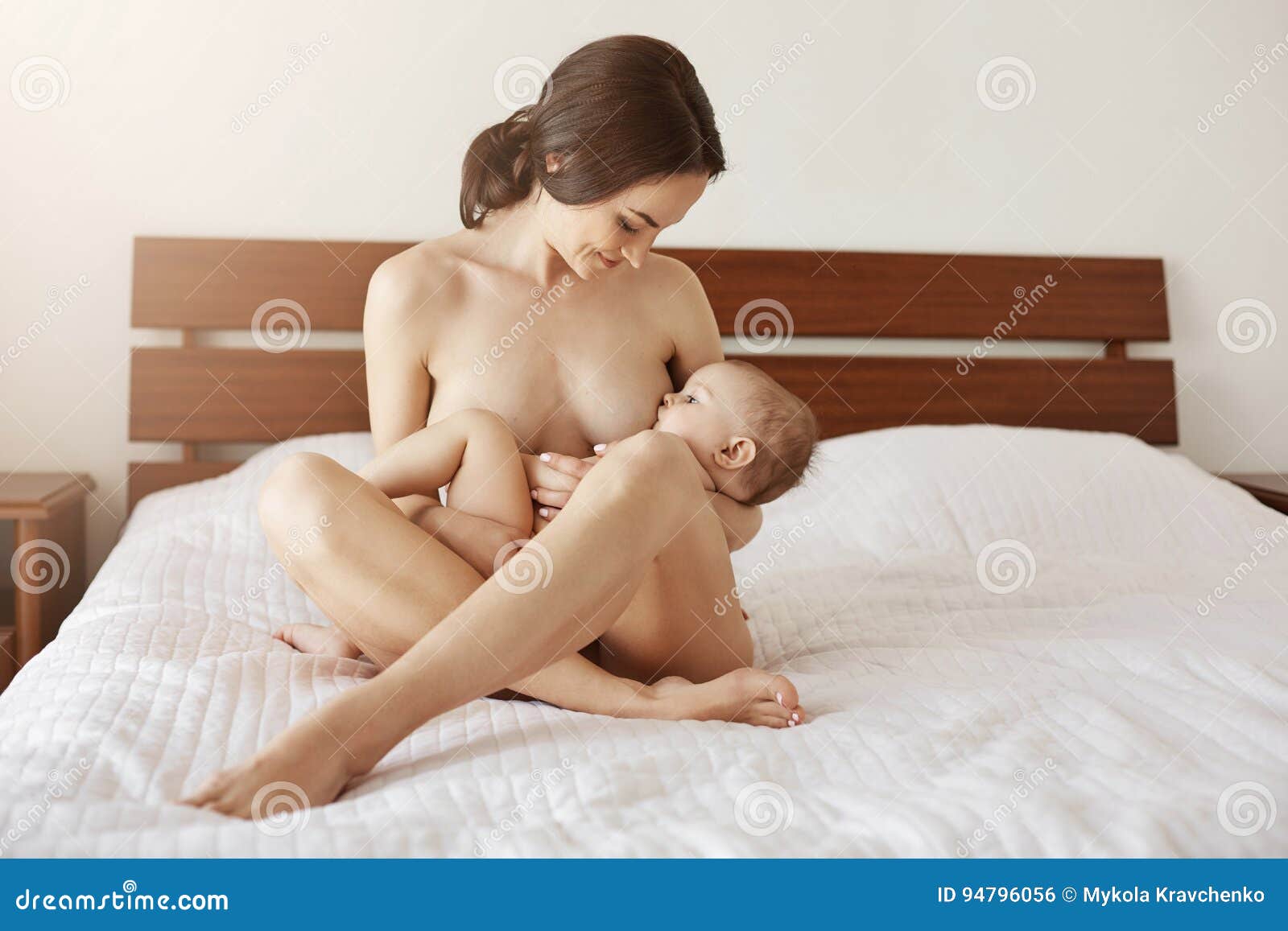 Молодая красивая нагая мама кормя грудью обнимающ ее сидеть Newborn младенц...