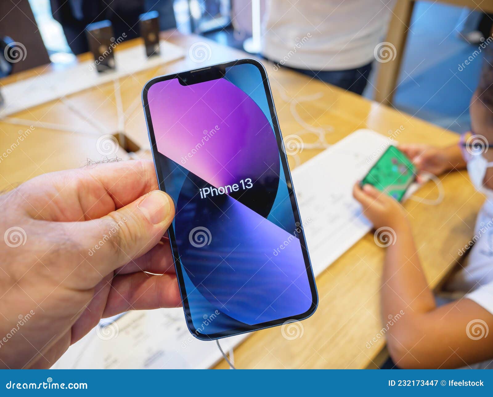 мужчина, держащий новый Iphone 13 в яблочном магазине с его красочными  обоями Редакционное Фотография - изображение насчитывающей дисплей, дело:  232173447