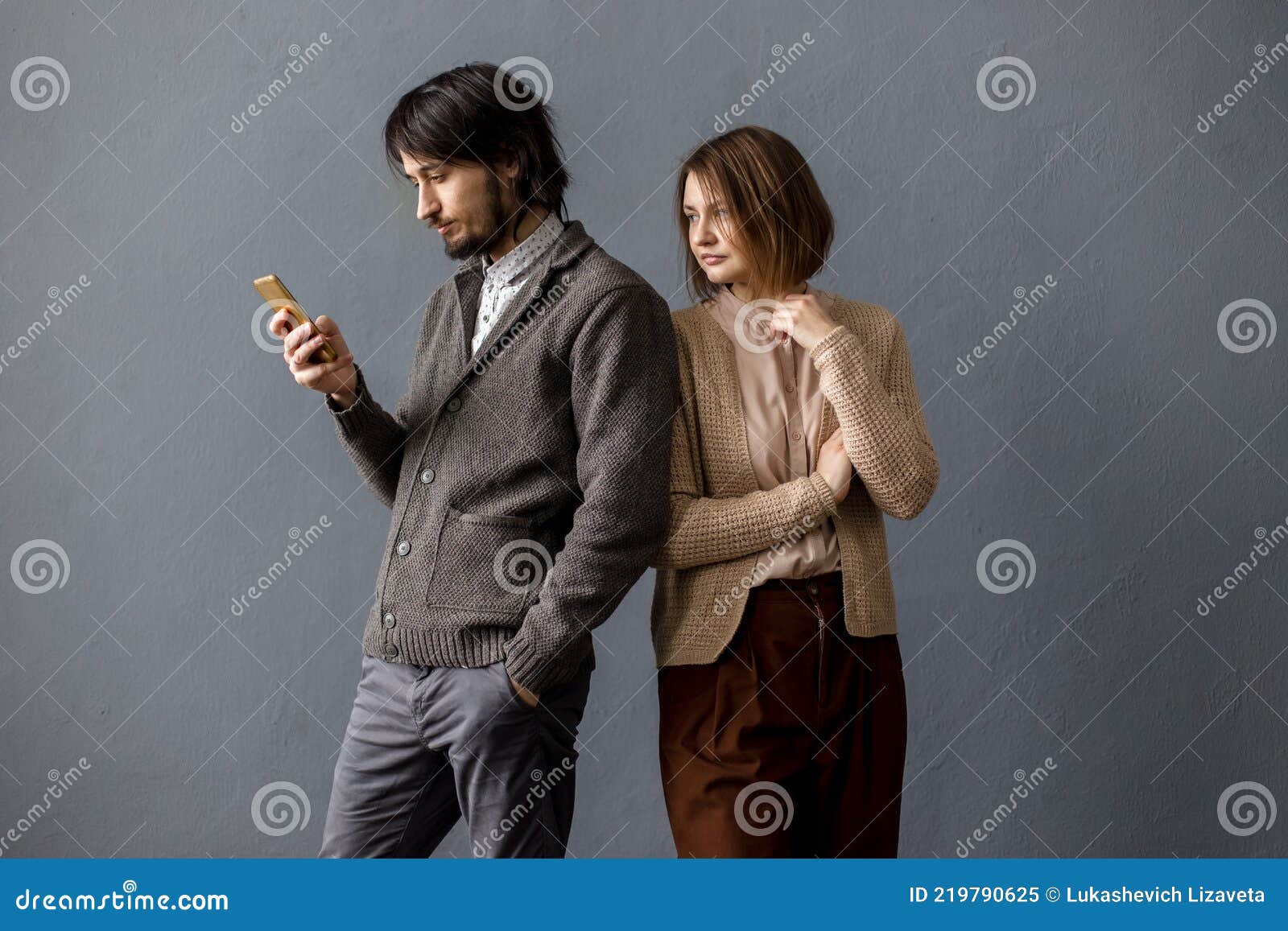 мужчина смотрит на телефон, а женщина смотрит сзади. серый фон. Стоковое  Изображение - изображение насчитывающей красиво, сообщение: 219790625