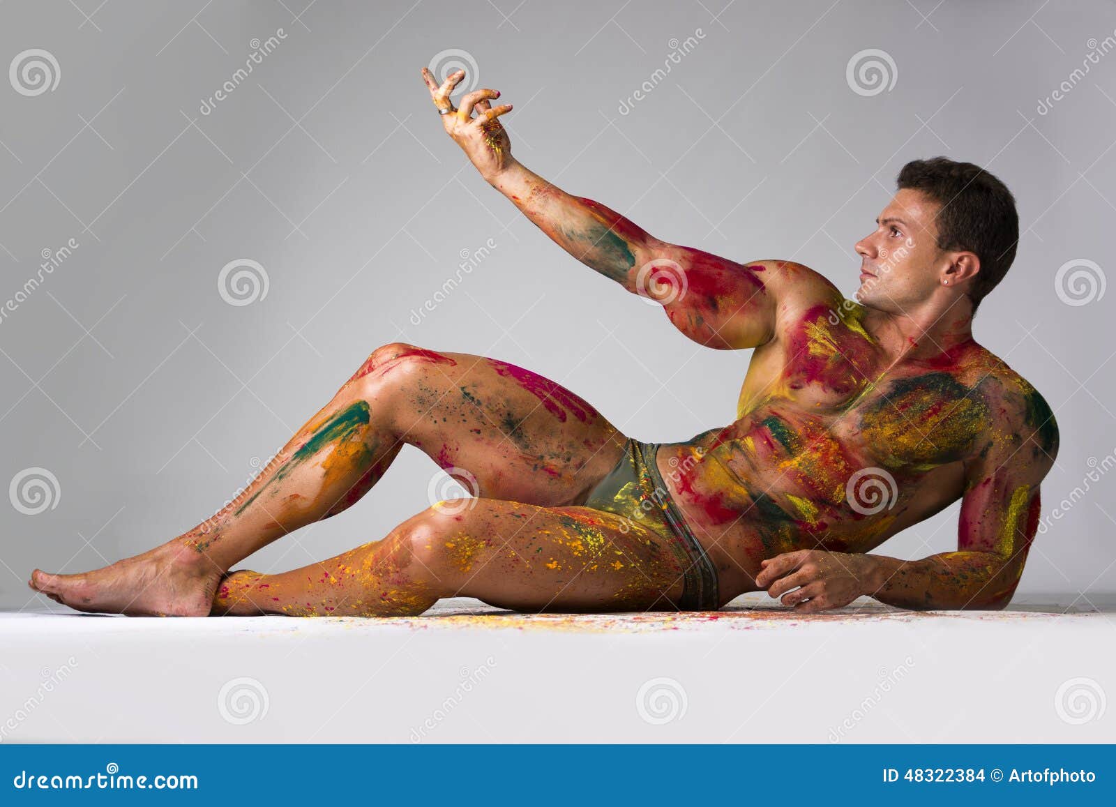 Мышечный молодой человек при кожа покрашенная при цвета Holi, кладя делает ...