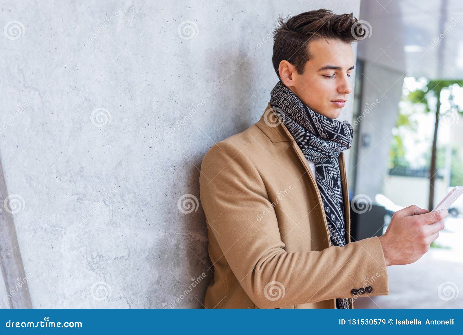 Odezhdy Zimy Molodogo Cheloveka Nosya V Ulice Ispolzuya Telefon Molodoj Paren S Sovremennym Stilem Prichesok S Palto Golubymi Dzhin Stokovoe Izobrazhenie Izobrazhenie Naschityvayushej Telefon Nosya 131530579
